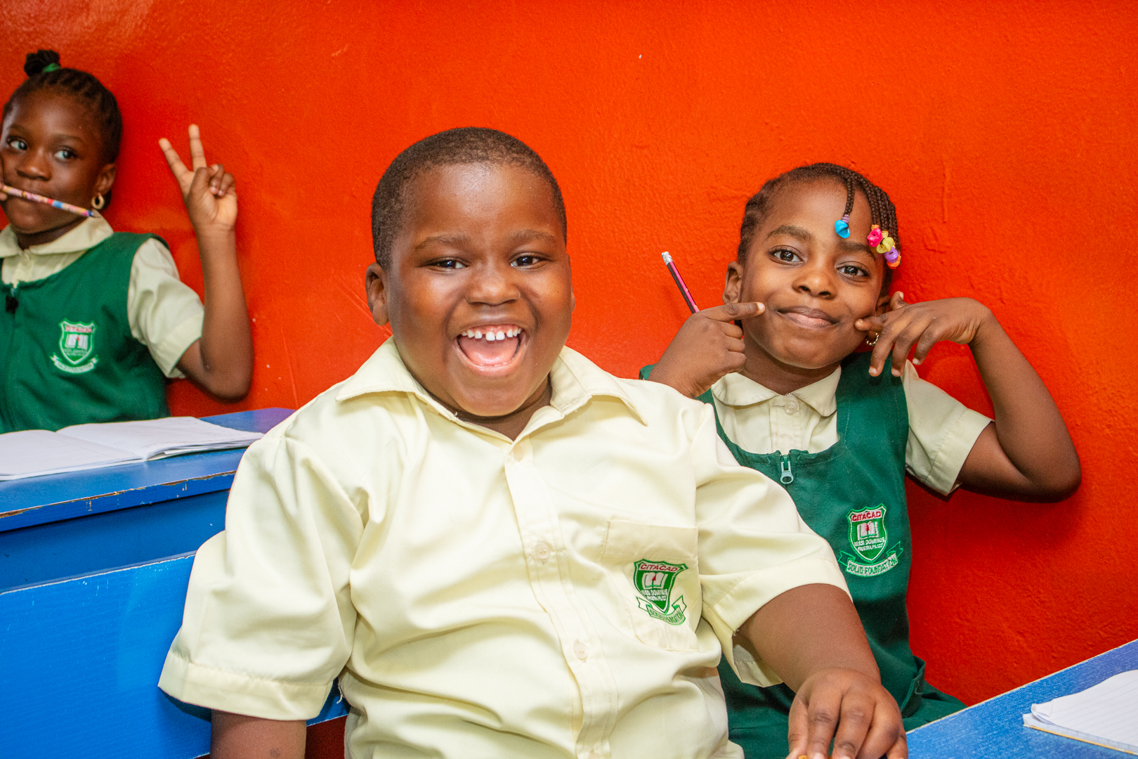 Three Citacad pupils smiling together in their classroom